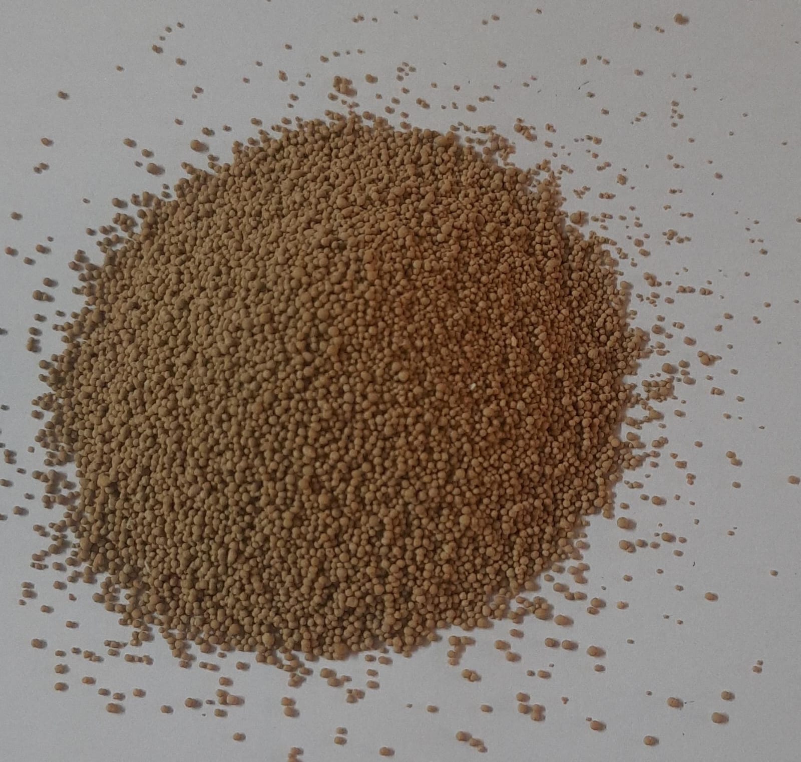 Flavomycin 8% granules — tan microbiological-grade poultry feed additive spread on a clean surface
